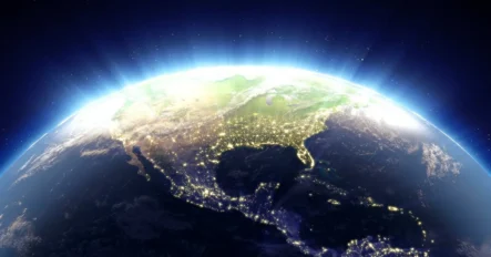 View of North America from space showing city lights across the continent, with the curvature of Earth and a glowing atmosphere visible against the dark background of space.