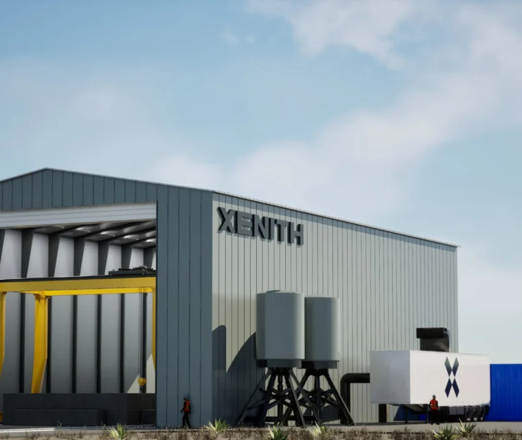A large industrial building labeled "XENITH" with storage tanks, two flags, and blue and white shipping containers outside; people are visible near the entrance.