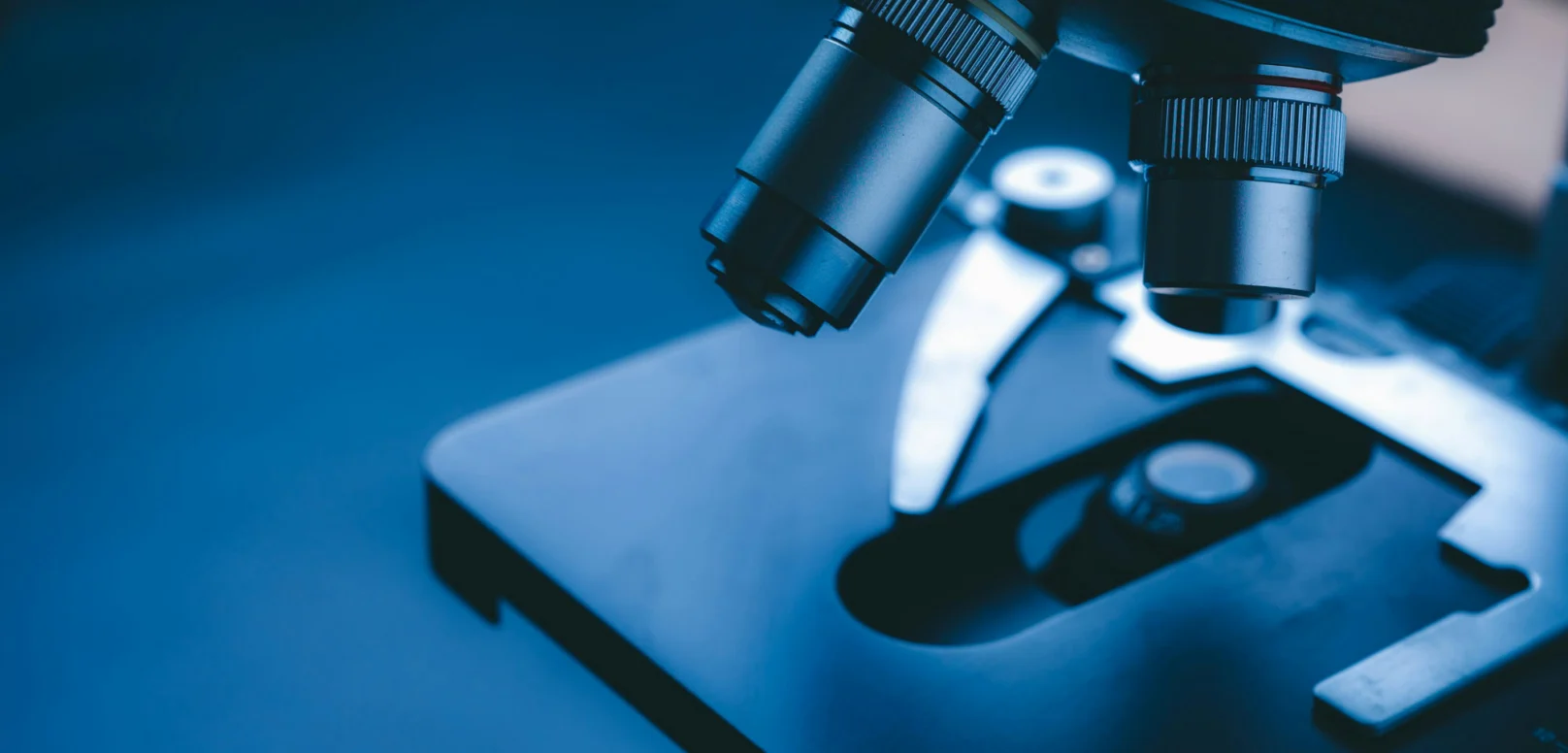 Close-up view of a microscope's objective lenses and stage in a laboratory setting.