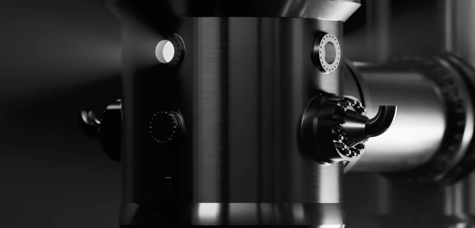 Close-up of a shiny, cylindrical industrial machine with various ports, knobs, and connected pipes, set against a dark background.