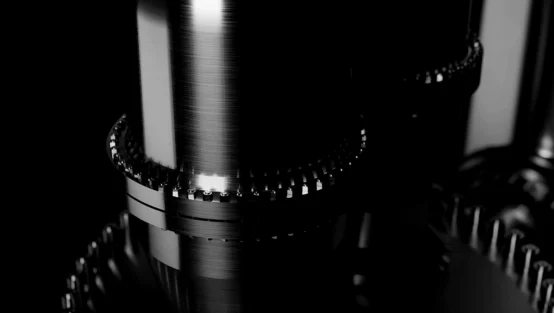 Close-up of polished metal gears interlocking in a dark, minimalistic industrial setting.