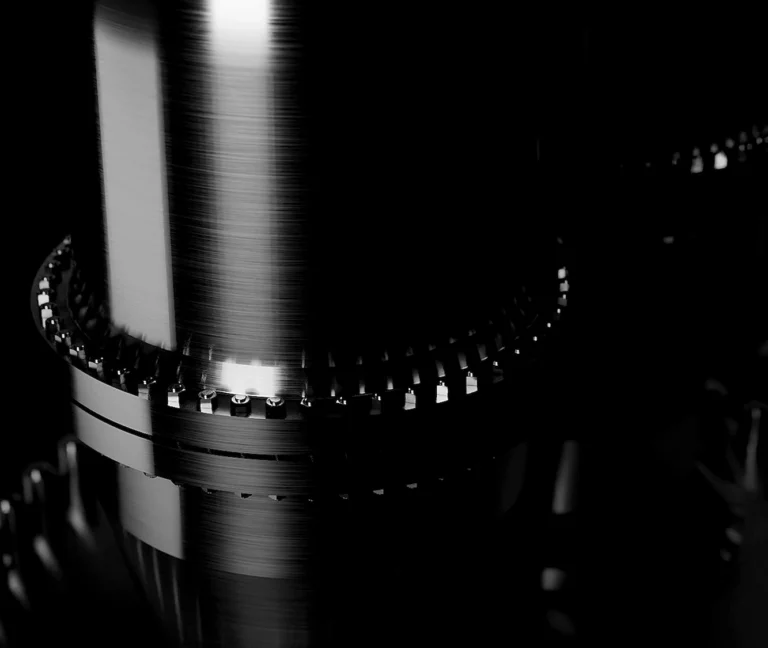 Close-up of polished metal gears interlocking in a dark, minimalistic industrial setting.