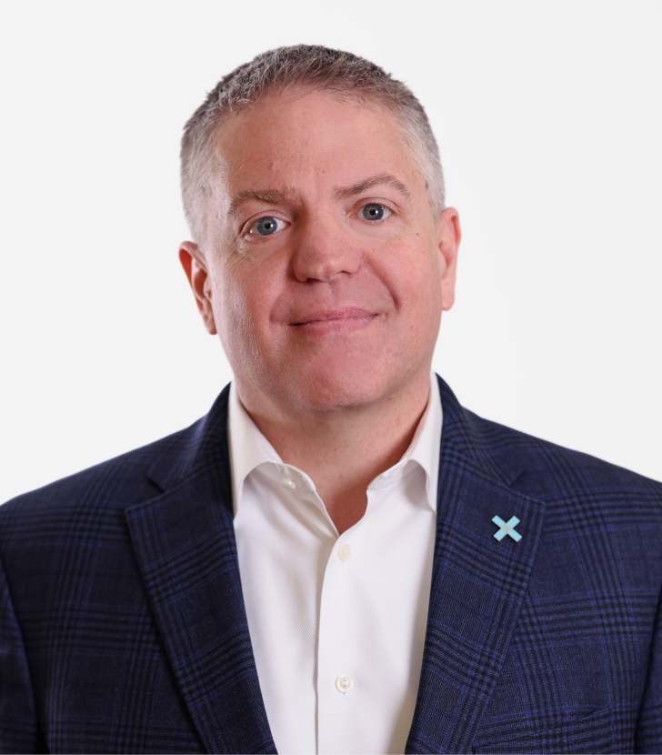 A man in a blue plaid jacket and white shirt poses for a professional headshot against a plain white background.