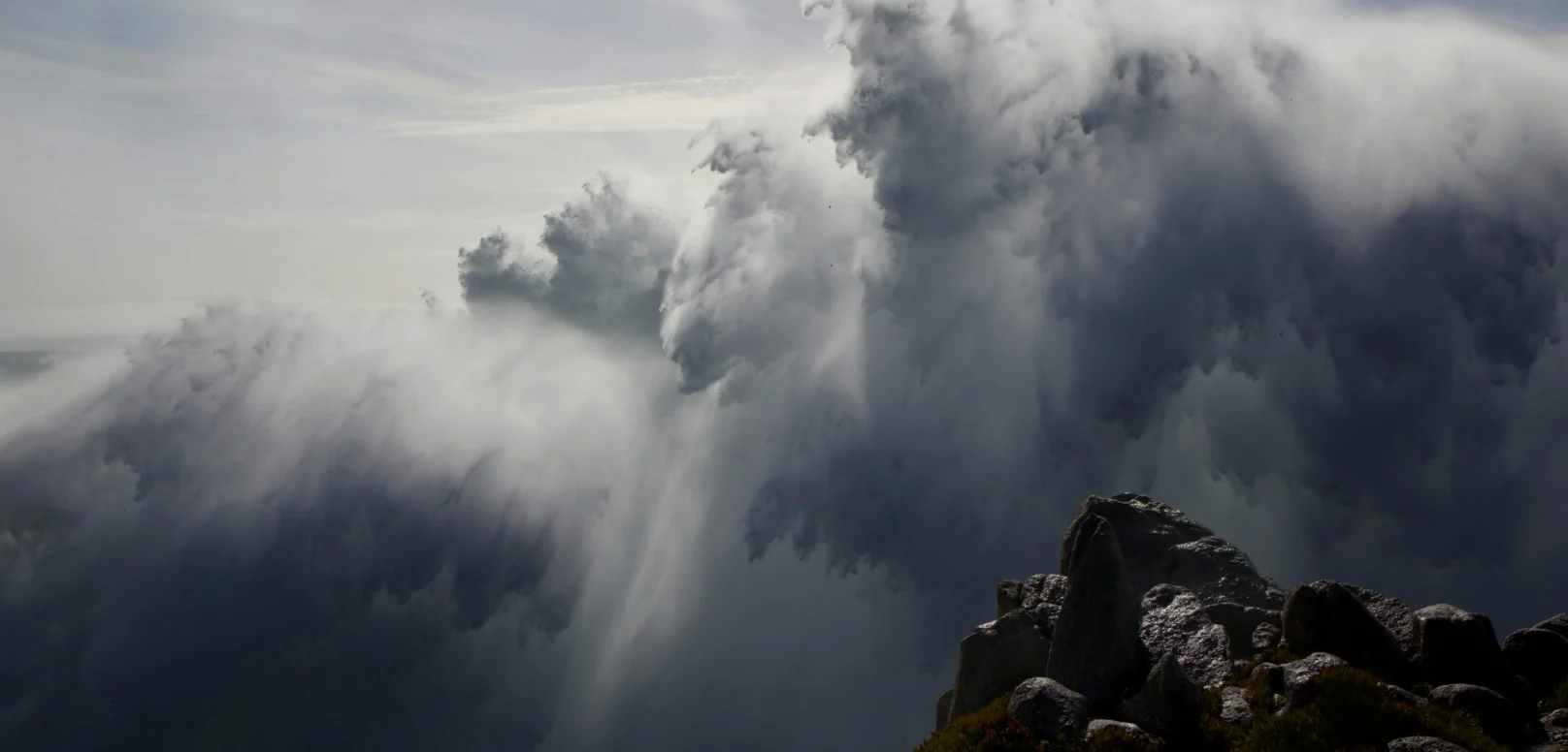 A large ocean wave crashes against a rocky cliff.